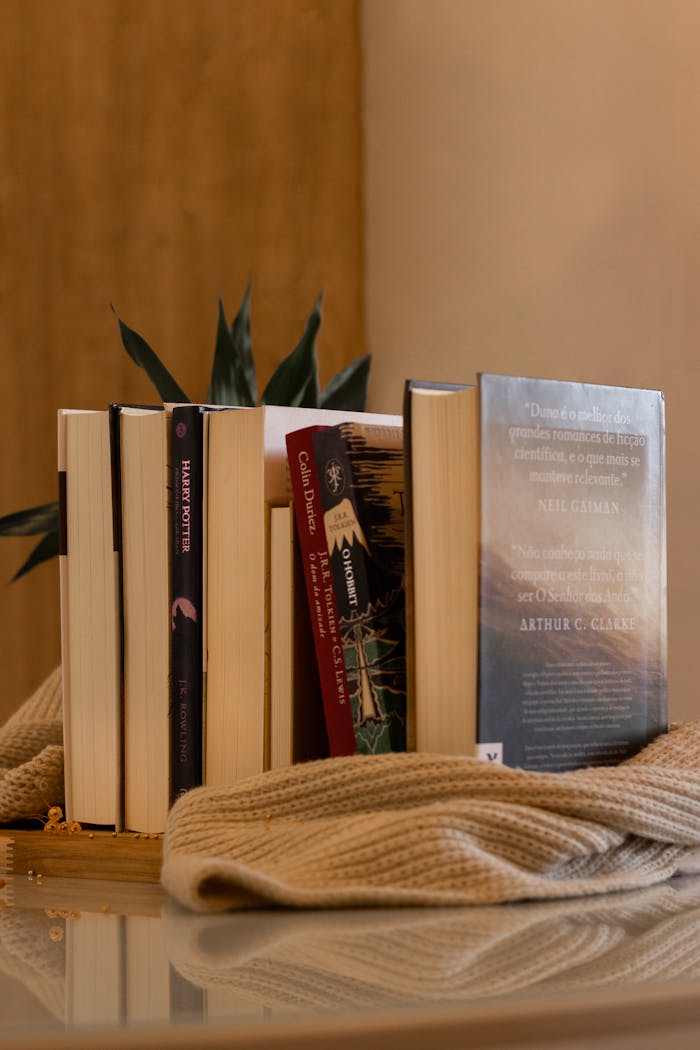 A collection of books arranged vertically on a table with a cozy cloth cover.