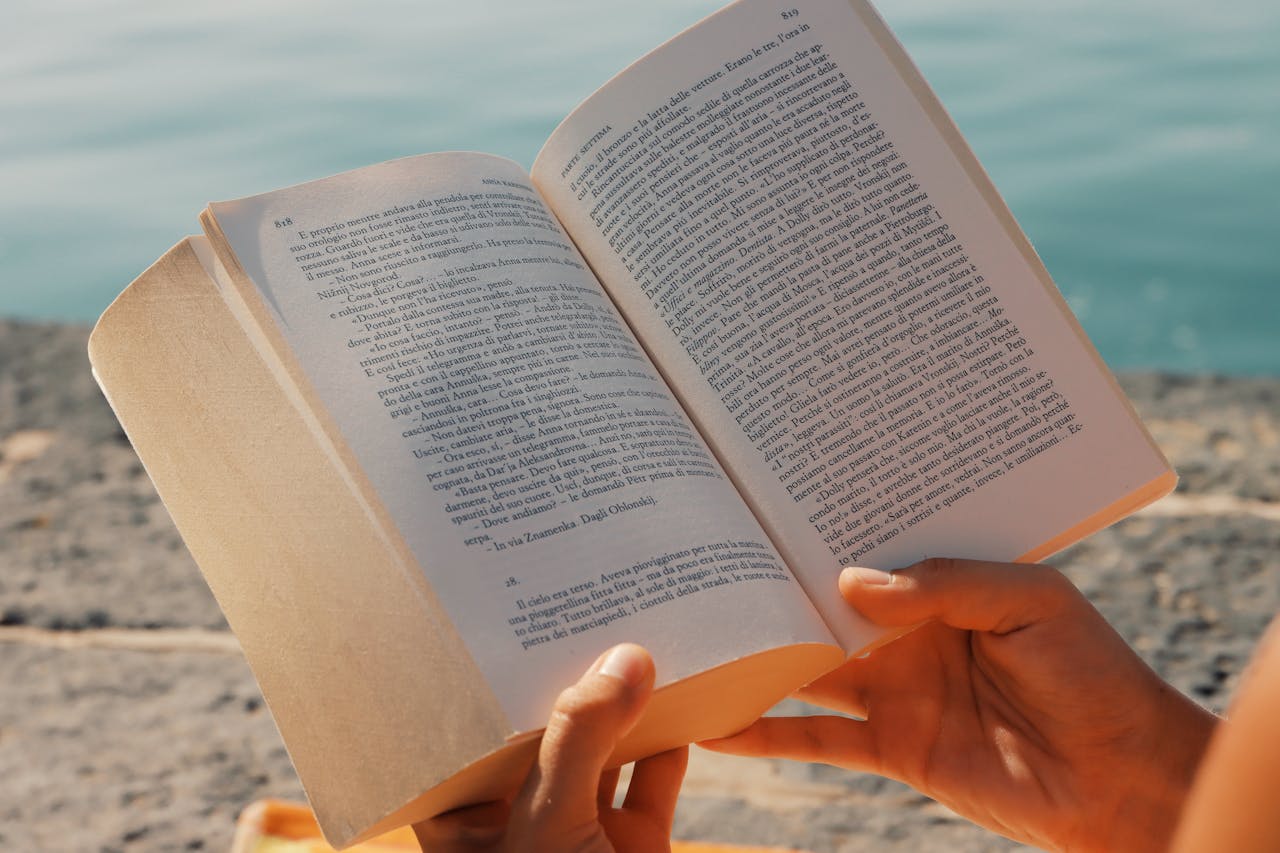 A person enjoys reading a book by the seaside in Syracuse, Sicily.