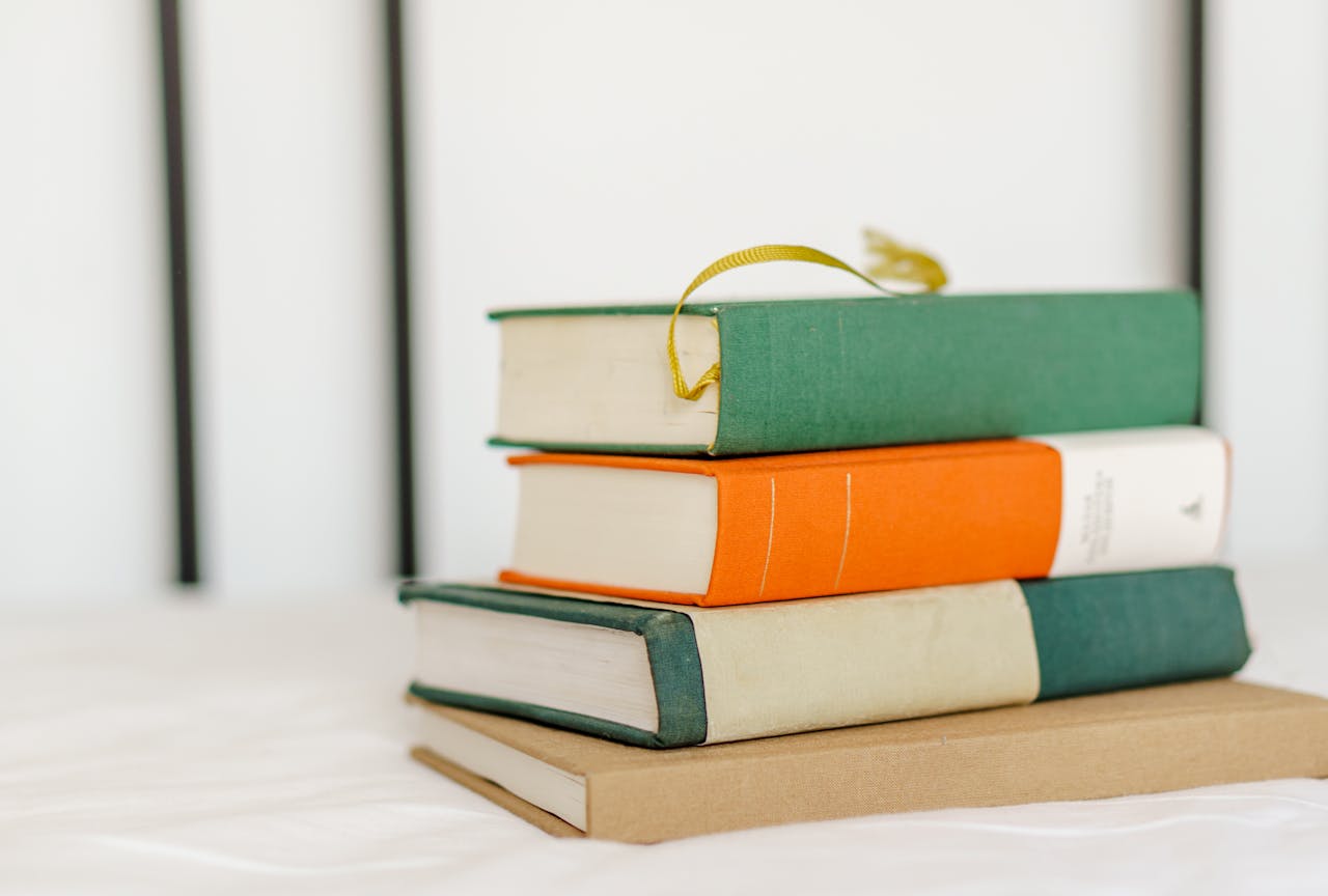 Pile of various books with multicolored covers on table in light room at home